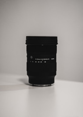 A sleek black and white photo of a camera lens with soft lighting highlighting its details.