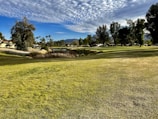 A picturesque view of a golf course surrounded by mountains and trees.