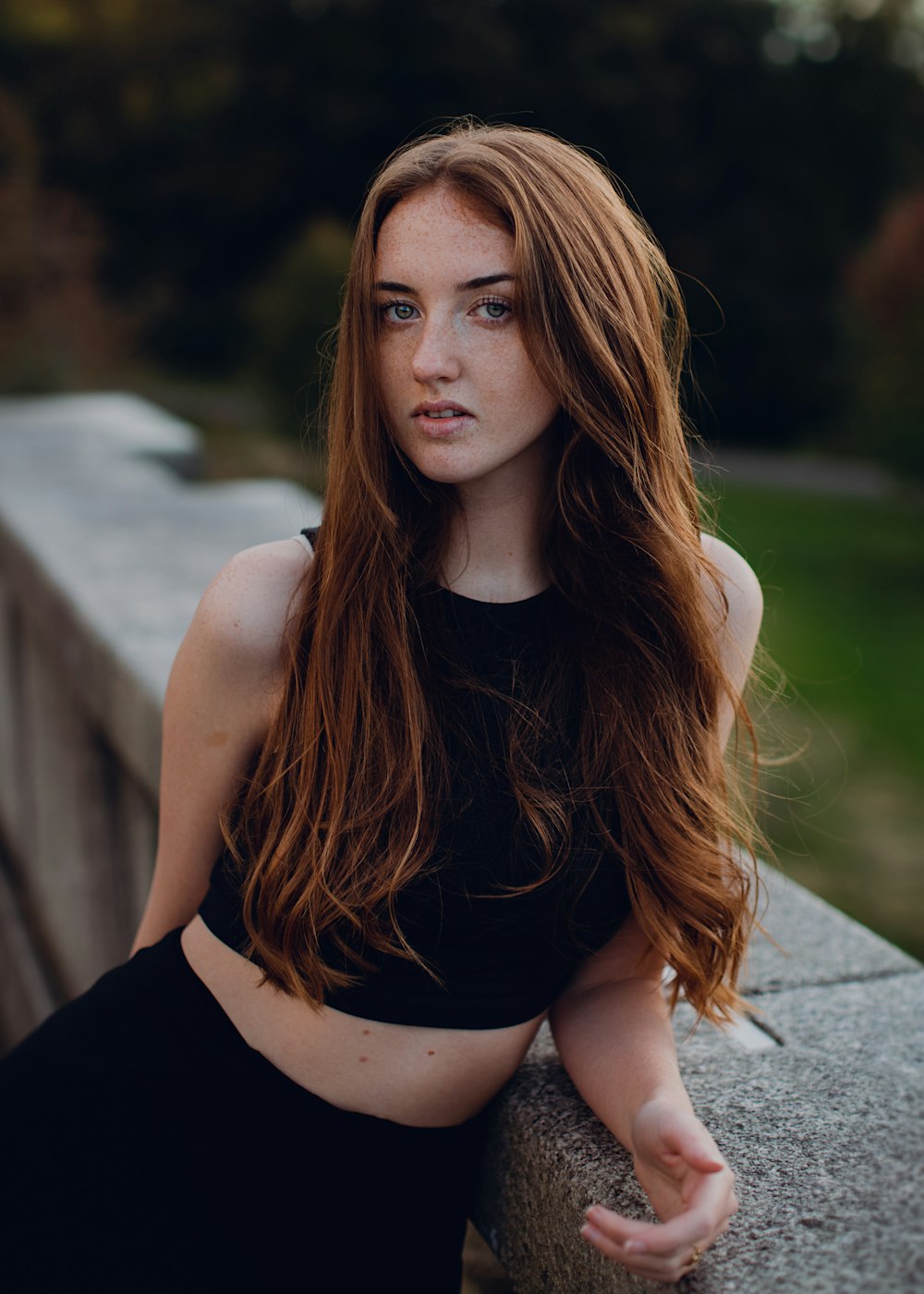 a woman with long red hair sitting on a ledge