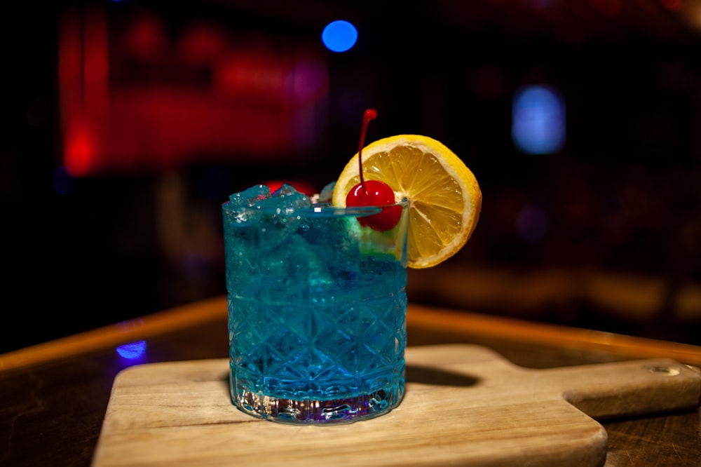 a blue cocktail with a cherry on the rim