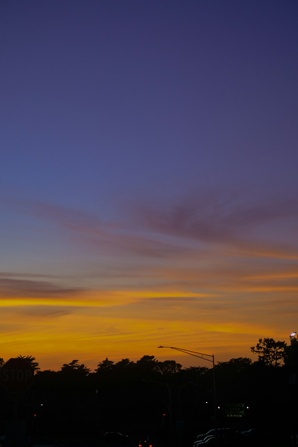 a sunset view of a city street with a clock tower in the distance