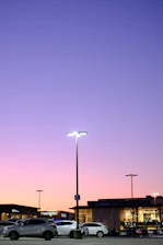A spacious motel parking lot with several cars parked under soft evening light.