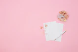 A flat lay featuring hot pink keychains, bookmarks, and pens arranged on a white background.