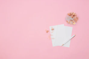 A flat lay featuring hot pink keychains, bookmarks, and pens arranged on a white background.