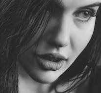 Close-up of a confident woman with a mysterious smile, highlighting allure.