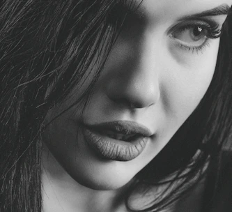 A close-up of a confident woman with a mysterious smile, evoking allure.