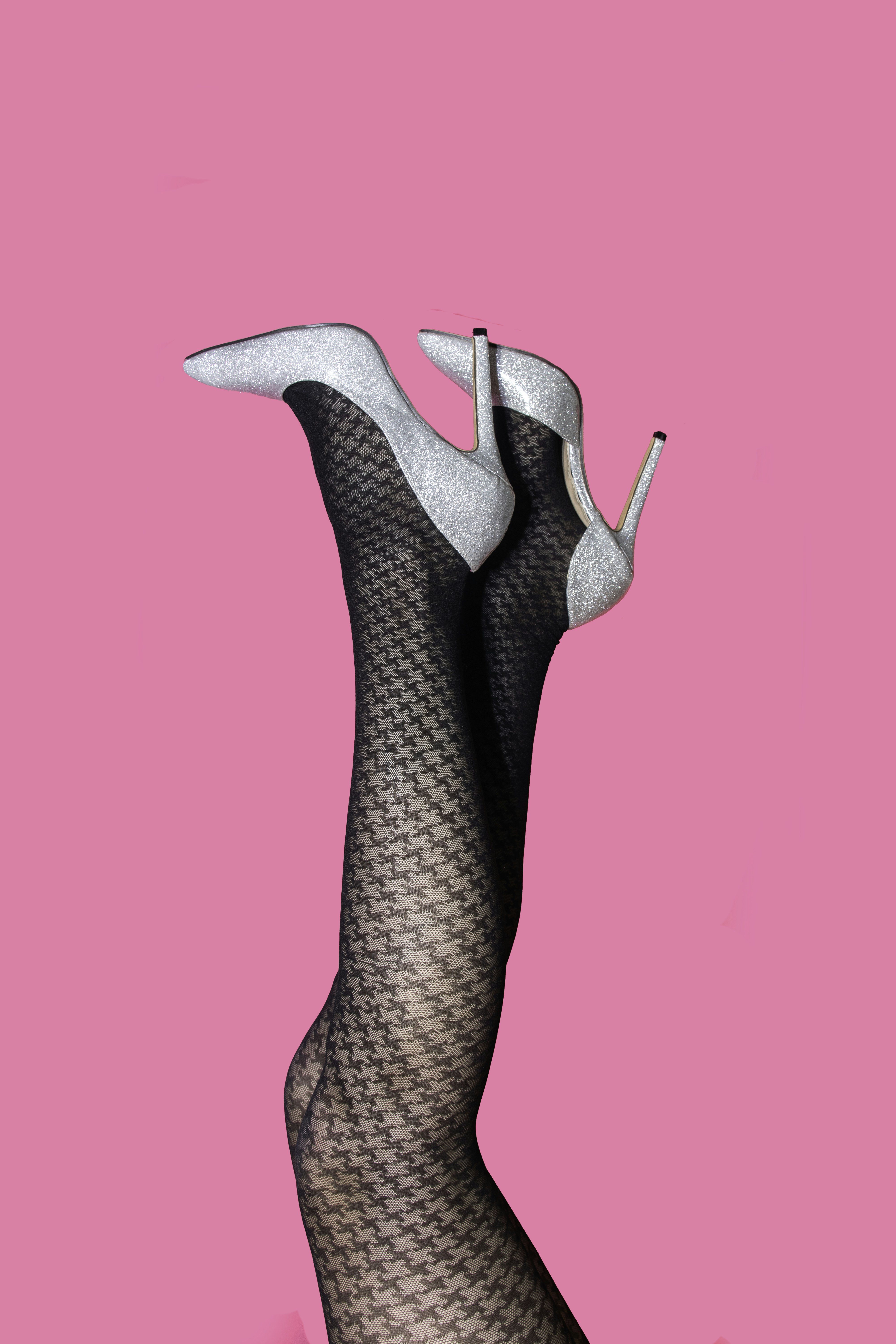 les jambes d’une femme en bas résille sur fond rose