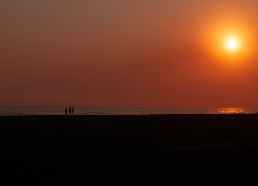 a couple of people standing on top of a sandy beach