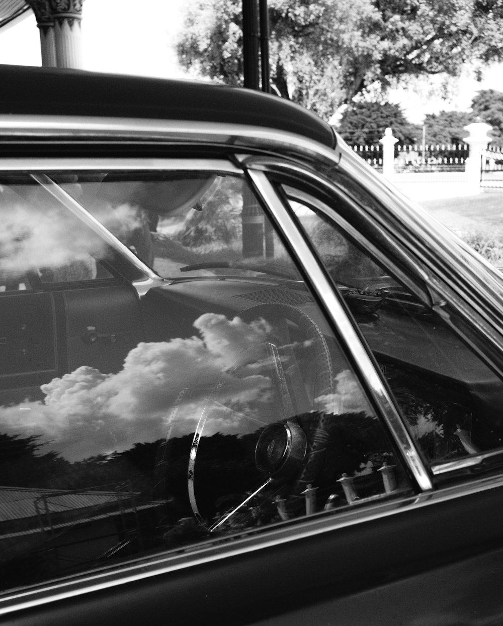 a black and white photo of clouds reflected in a car window