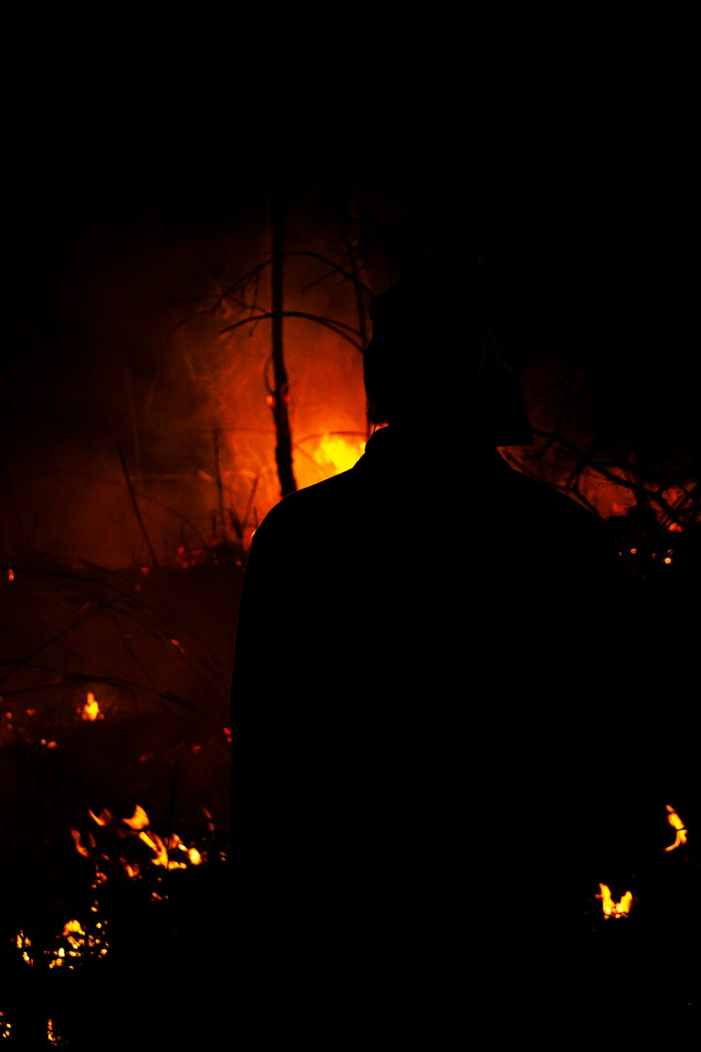 a man standing in front of a fire in the dark