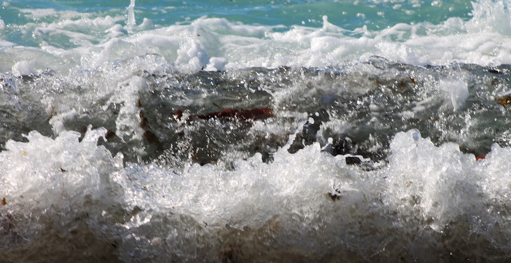 the water is splashing on the rocks near the shore