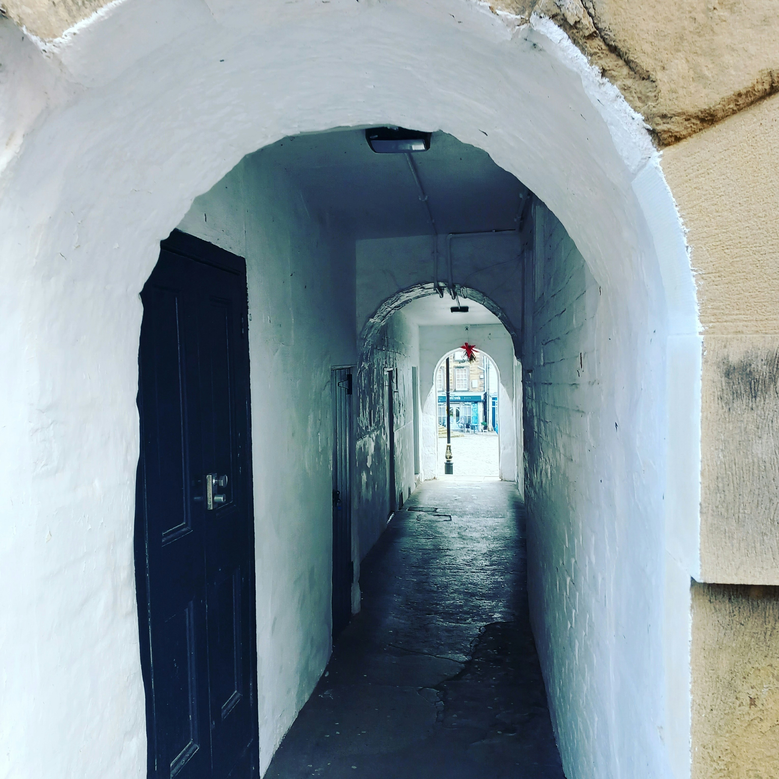uno stretto corridoio con una porta blu e pareti bianche