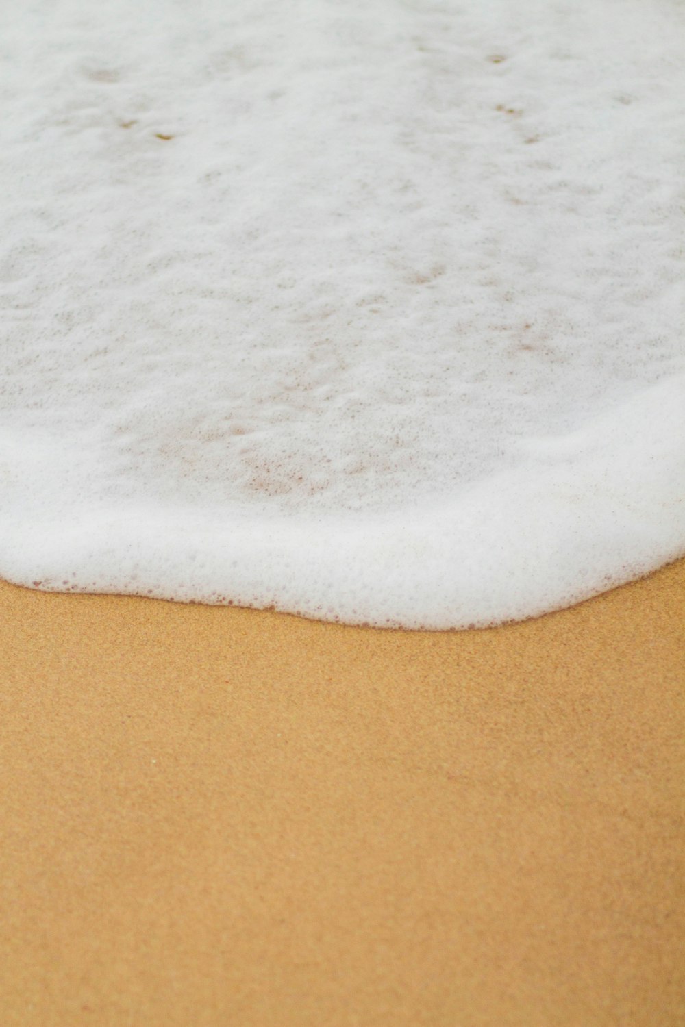 a close up of a wave on a sandy beach