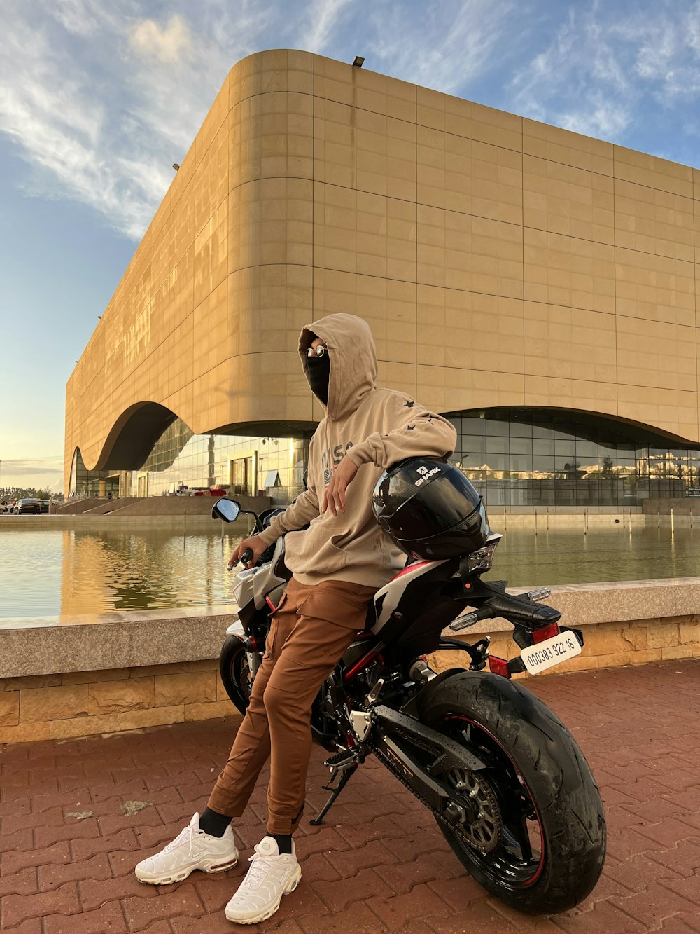 Un homme assis sur une moto devant un immeuble