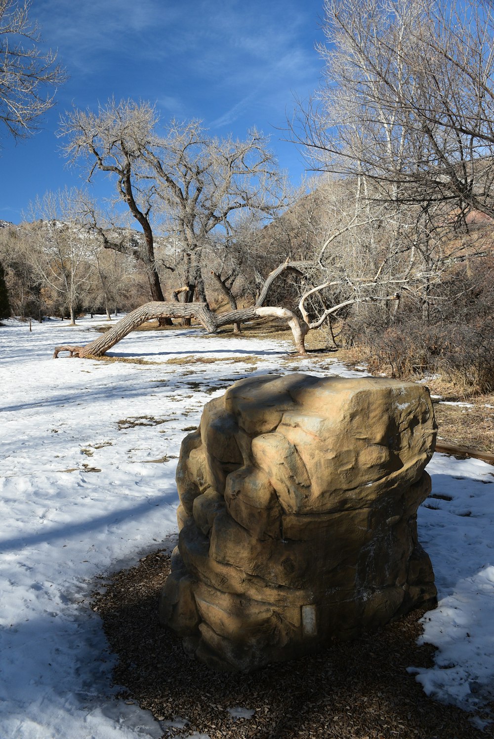 a large rock sitting in the middle of a snow covered field