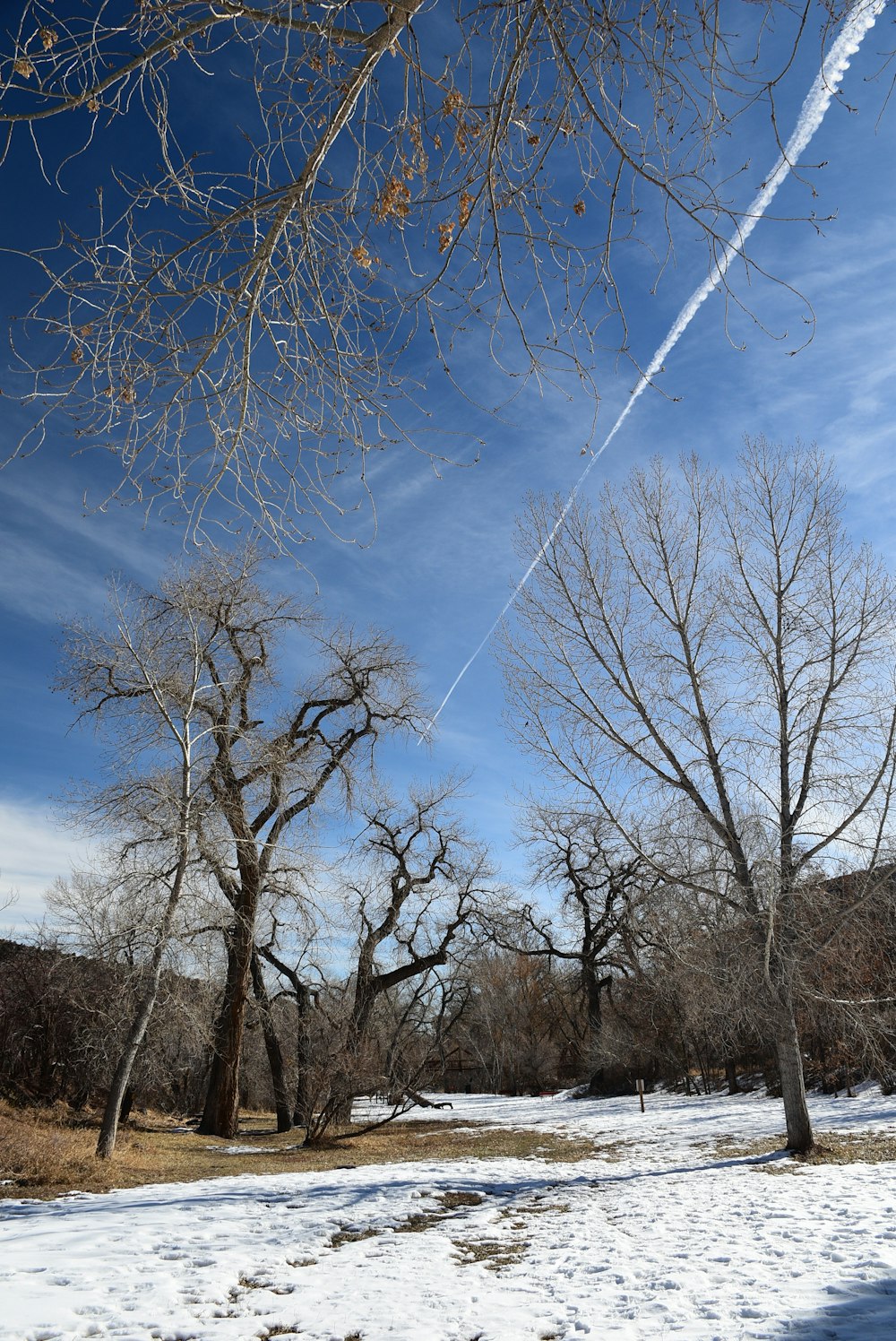 a plane flying in the sky over a snow covered field