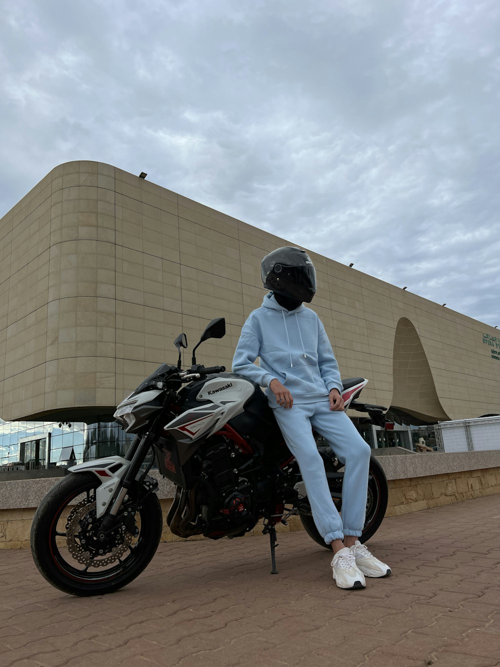 a person sitting on a motorcycle in front of a building