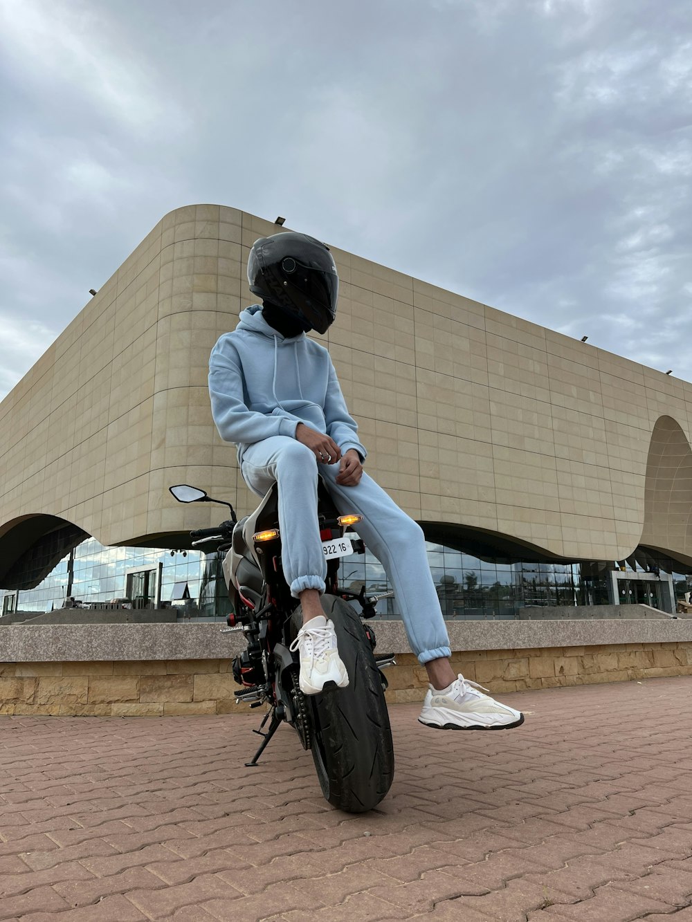 une personne assise sur une moto devant un immeuble