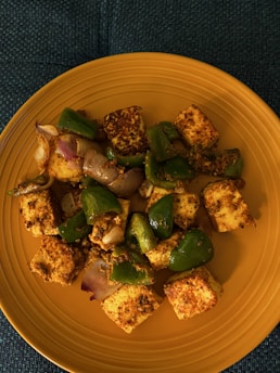 A close-up of creamy paneer cubes on a wooden cutting board, surrounded by fresh herbs.