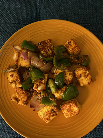 A vibrant bowl of paneer tikka made with golden moong dal tofu, garnished with lime and coriander.