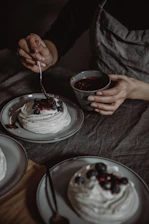 Close-up of hands delicately decorating a healthy, traditional dessert with fresh berries.