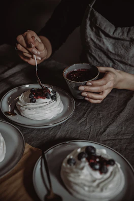 A chef carefully adding final touches to a delicate cake topped with fresh berries