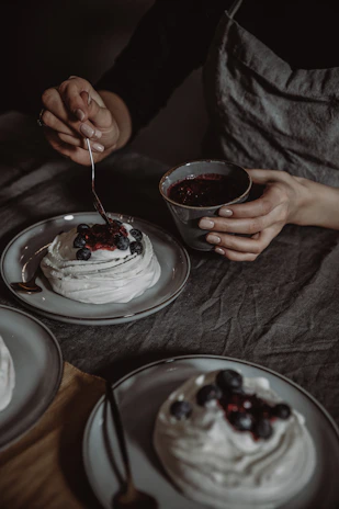 Close-up of hands delicately decorating a healthy, traditional dessert with fresh berries.