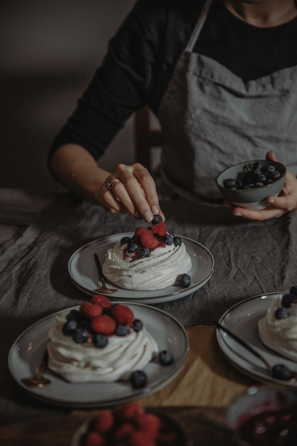 a woman is decorating a cake with berries