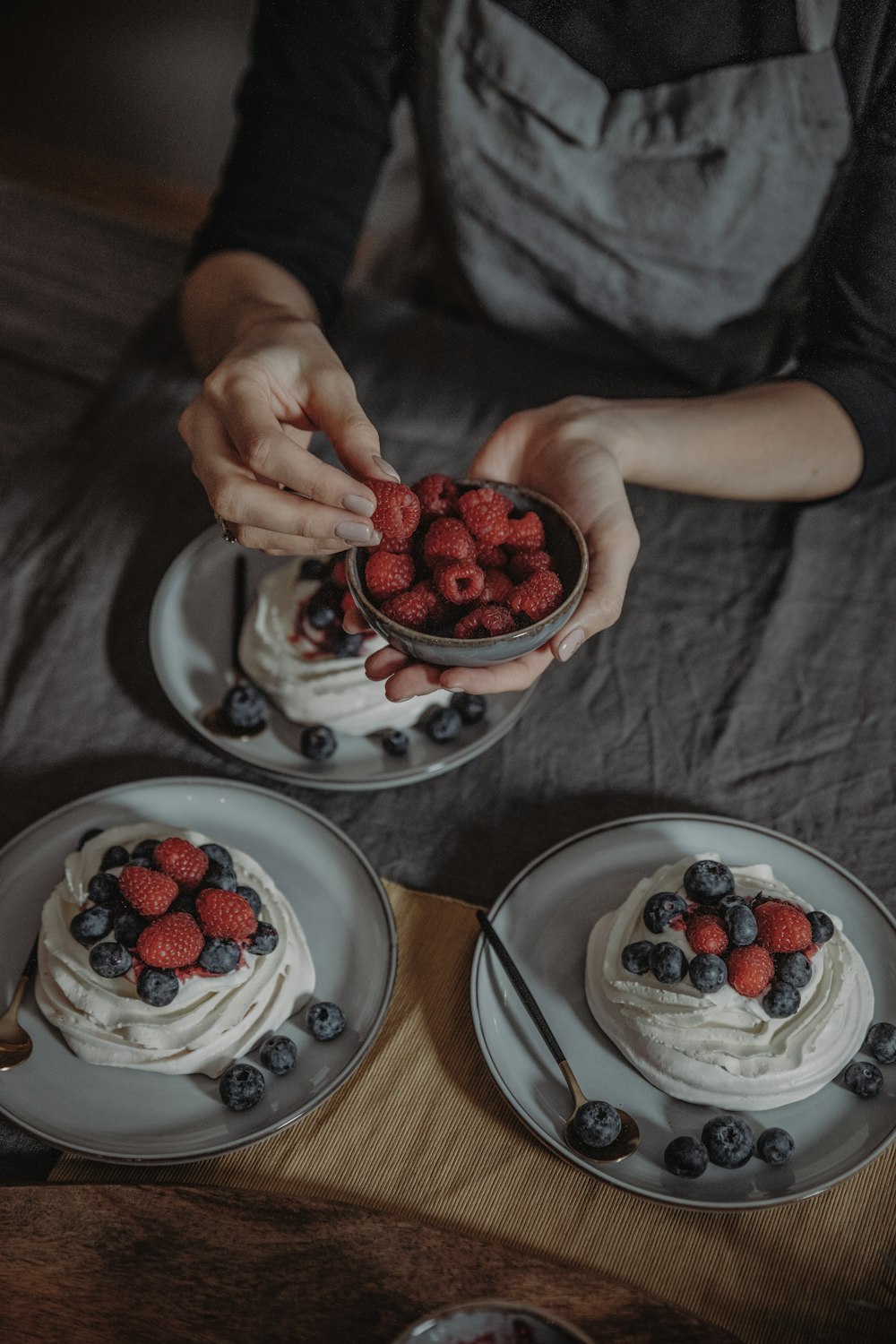 a person holding a bowl of berries on top of a cake