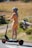 Customer Alice W. riding her electric scooter outdoors.