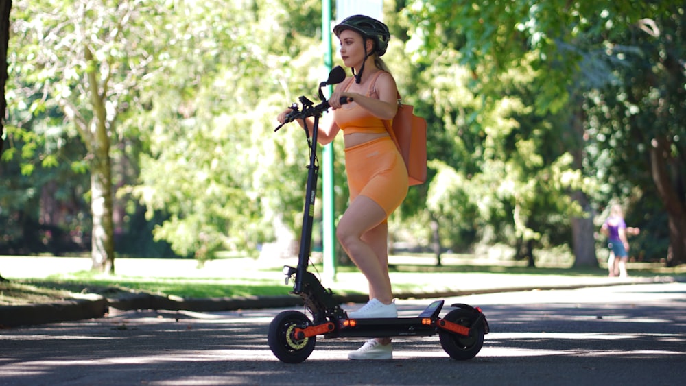 a woman in an orange dress riding a scooter