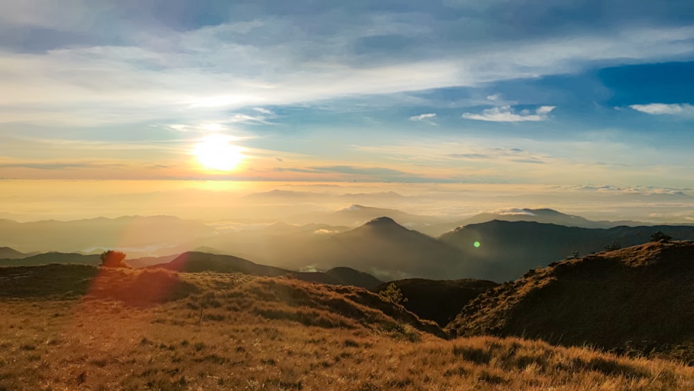 the sun is setting over the mountains in the distance