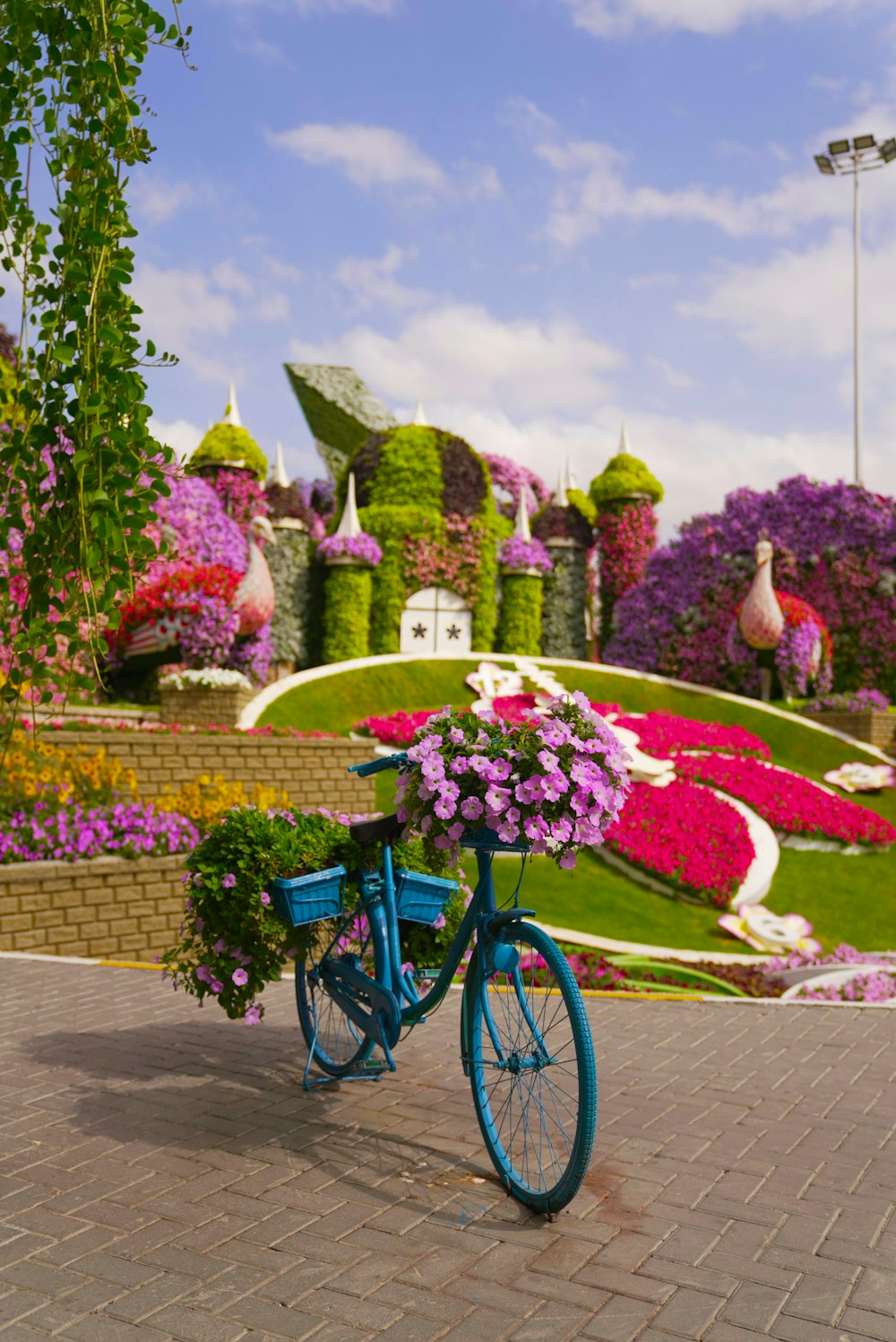 Una bicicletta blu con fiori sul retro parcheggiata di fronte a un giardino  fiorito foto – Erba Immagine gratuita su Unsplash