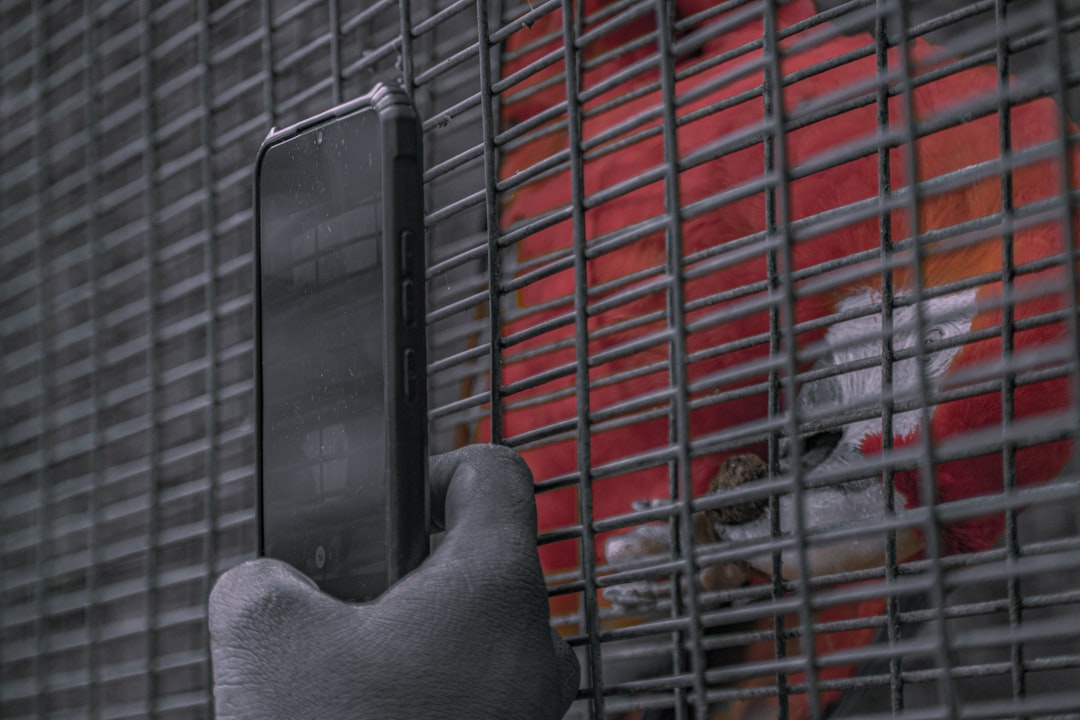 a person holding a cell phone in front of a cage,