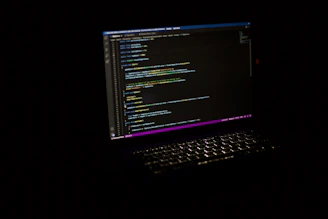 Close-up of hands typing code on a laptop with colorful syntax highlighting.