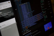 Close-up of hands coding a website with blue design elements on screen.