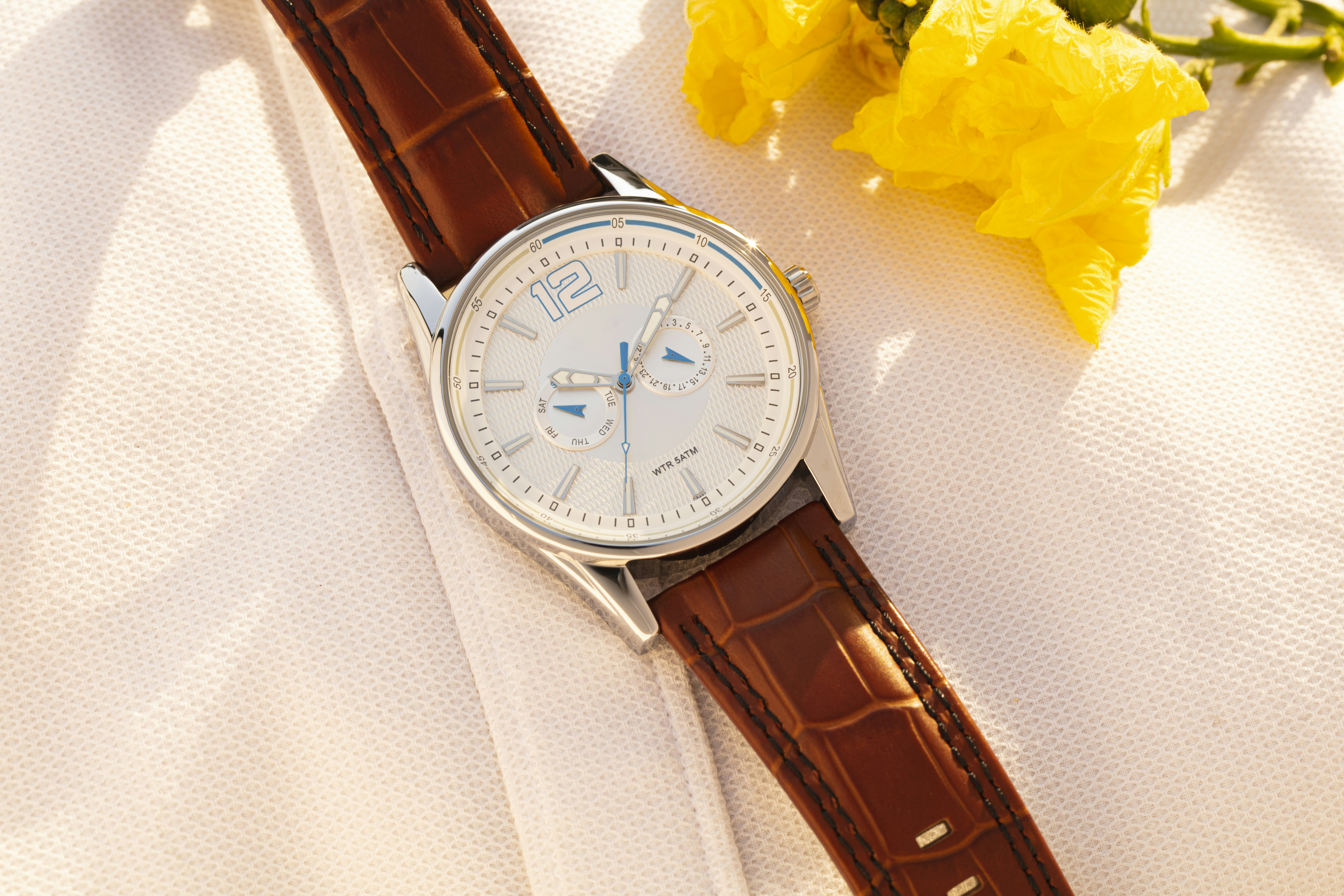 黄色い花の隣に白い布の上に座っている時計