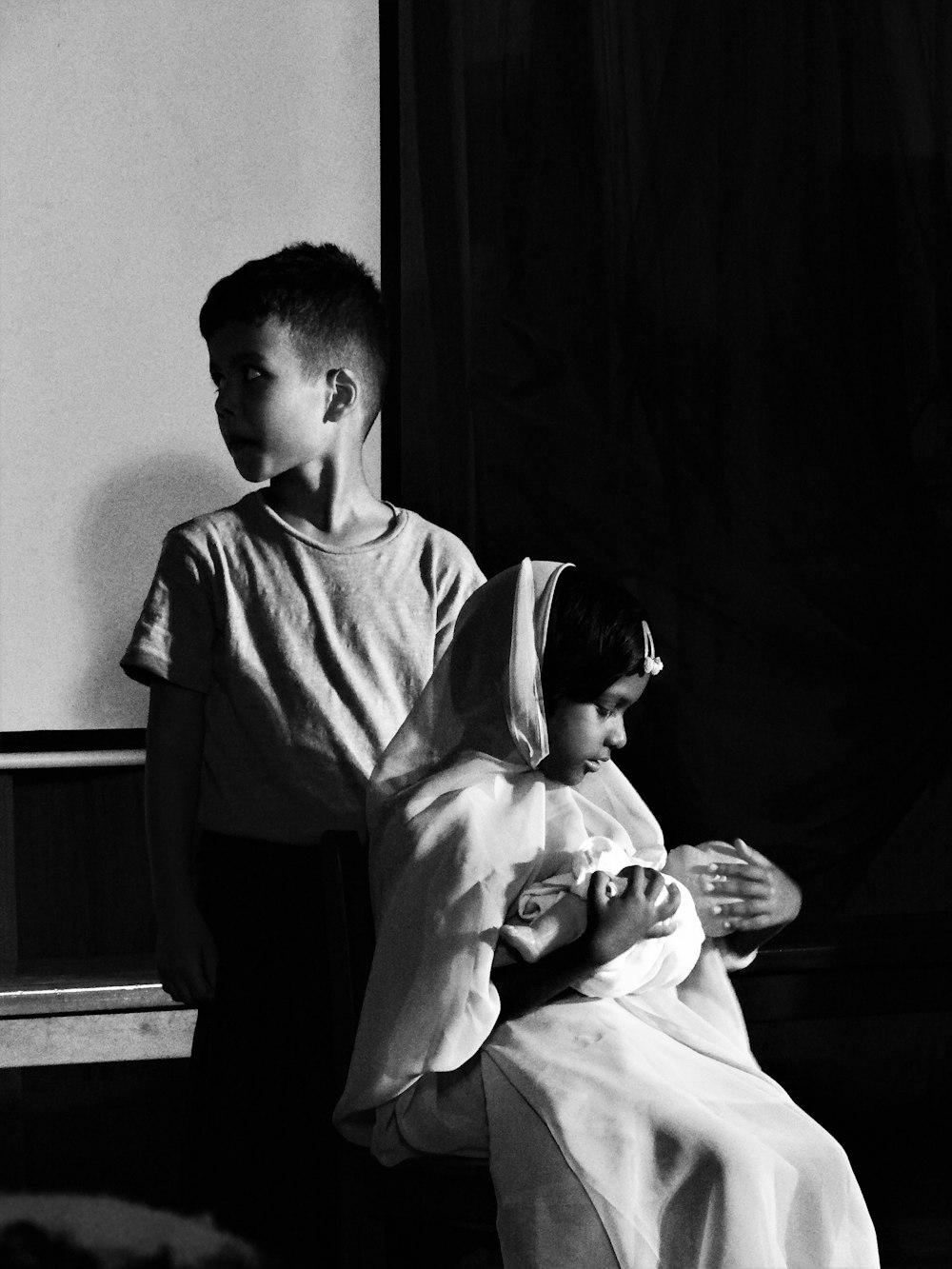 a black and white photo of a young boy holding a baby