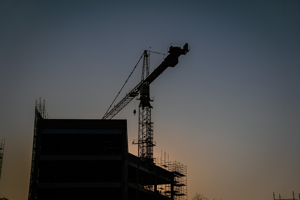 a crane is silhouetted against the evening sky