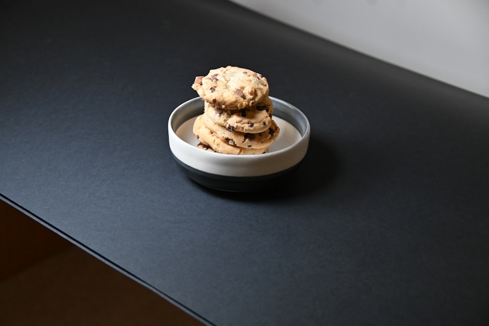 three chocolate chip cookies in a bowl on a black counter