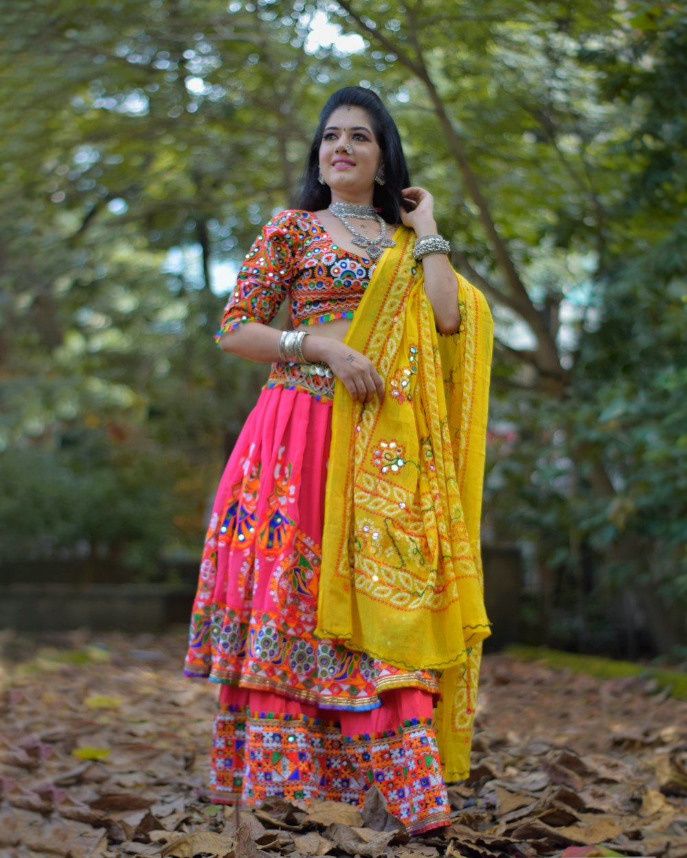 a woman in a colorful dress standing in leaves