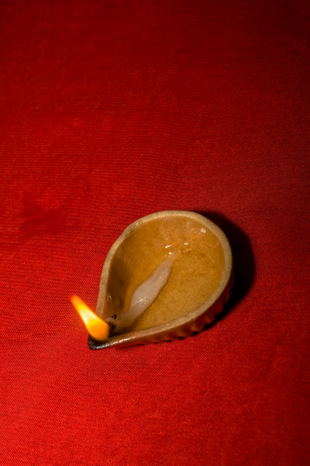 a spoon with a candle in it on a red surface