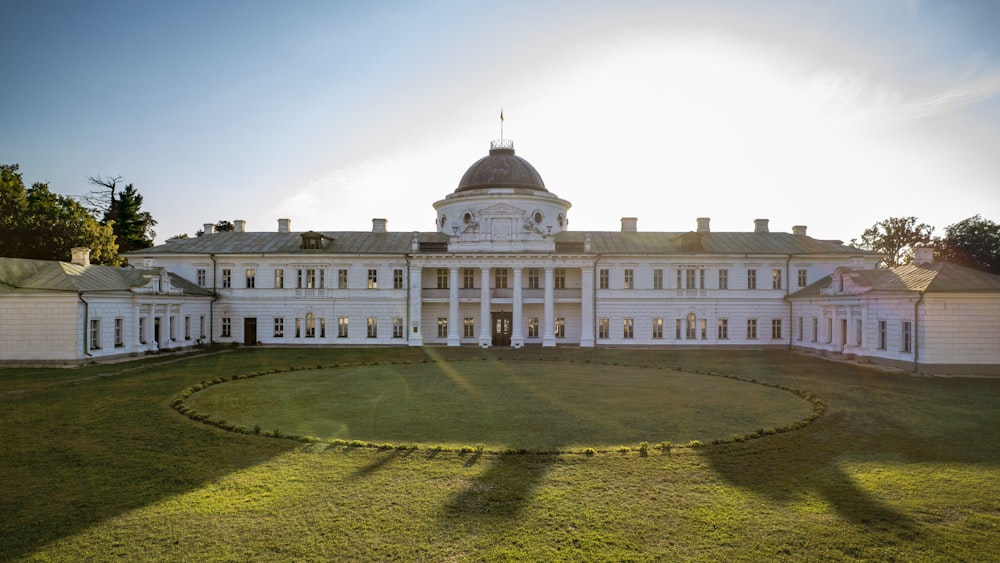 a large white building with a circular lawn in front of it