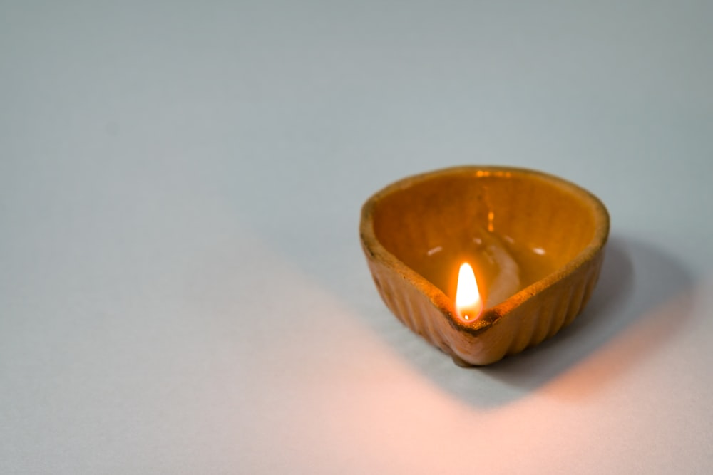 a lit candle sitting in a bowl on a table