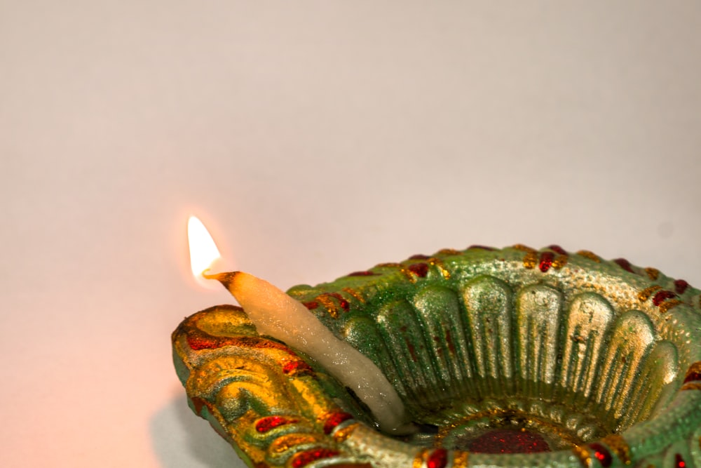 a lit candle sitting in a decorative bowl