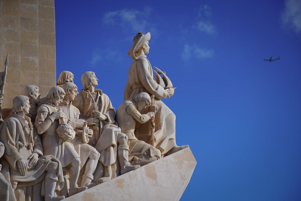 a statue of a group of people with a plane in the background