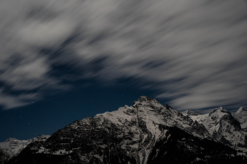 a mountain covered in snow under a cloudy sky