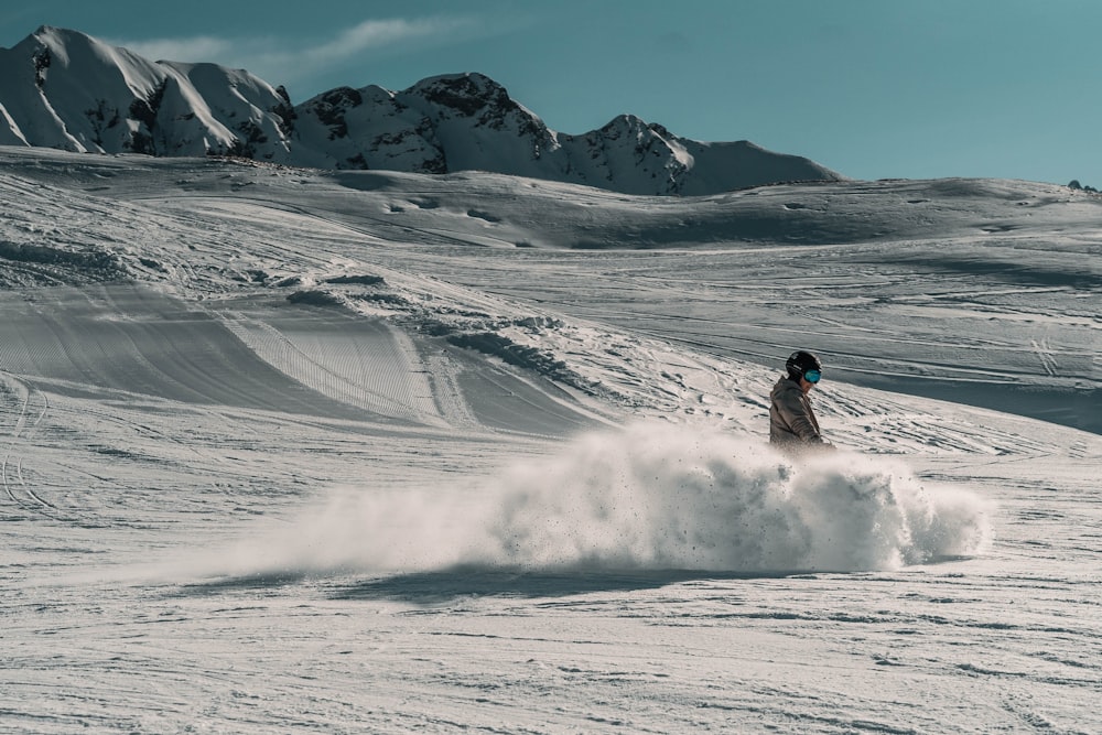 a person riding a snowboard down a snow covered slope