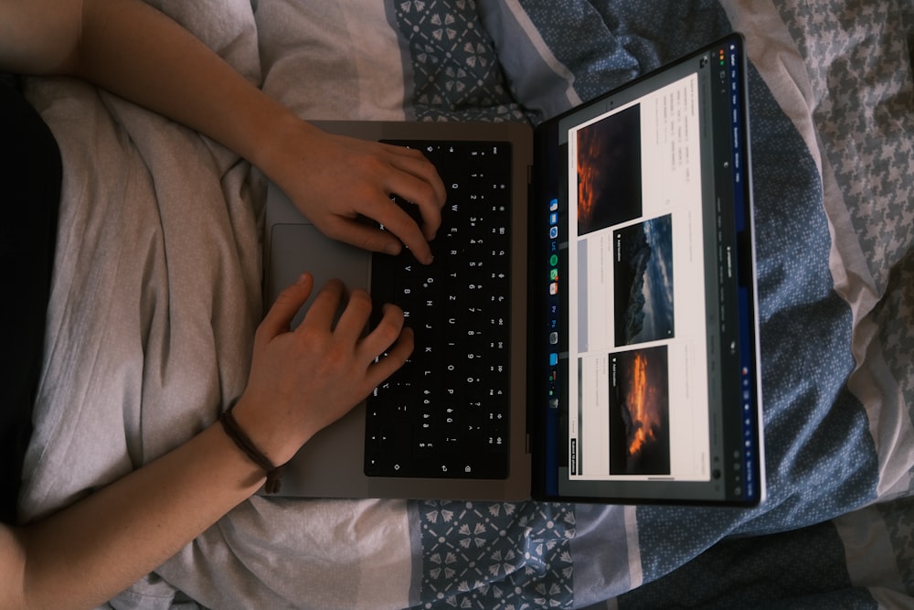 a person using a laptop computer on a bed