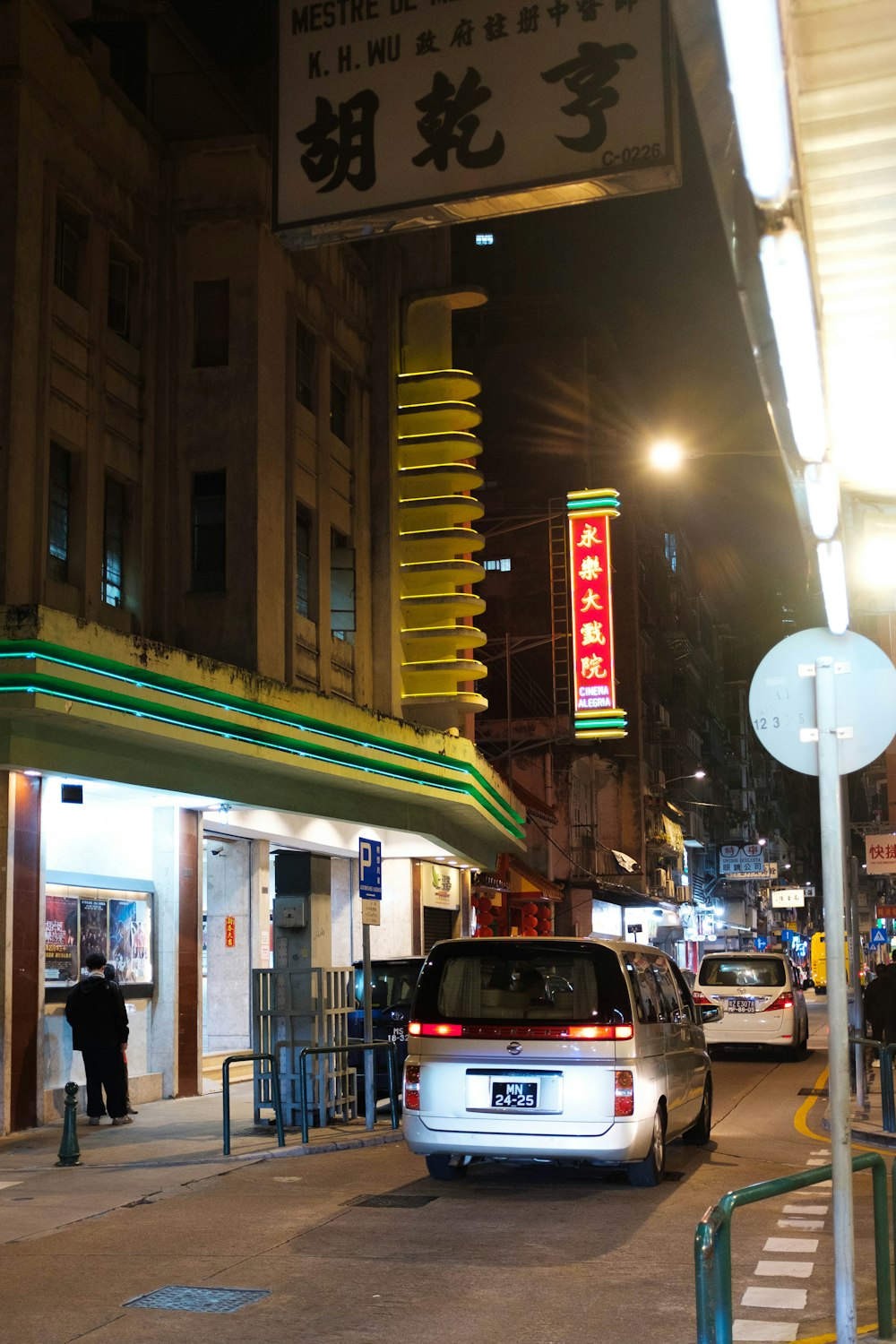 a city street at night with cars parked on the side of the road